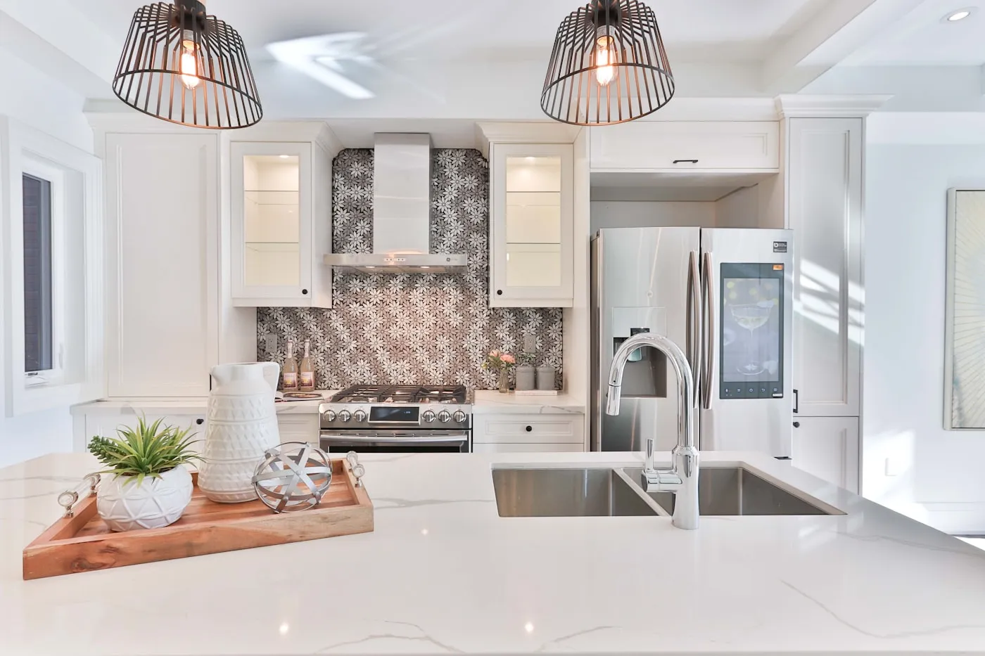 Quartz counter with a patterned tile backsplash and pendant lights